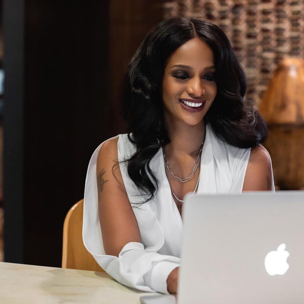 A woman sitting at a table with an apple laptop.