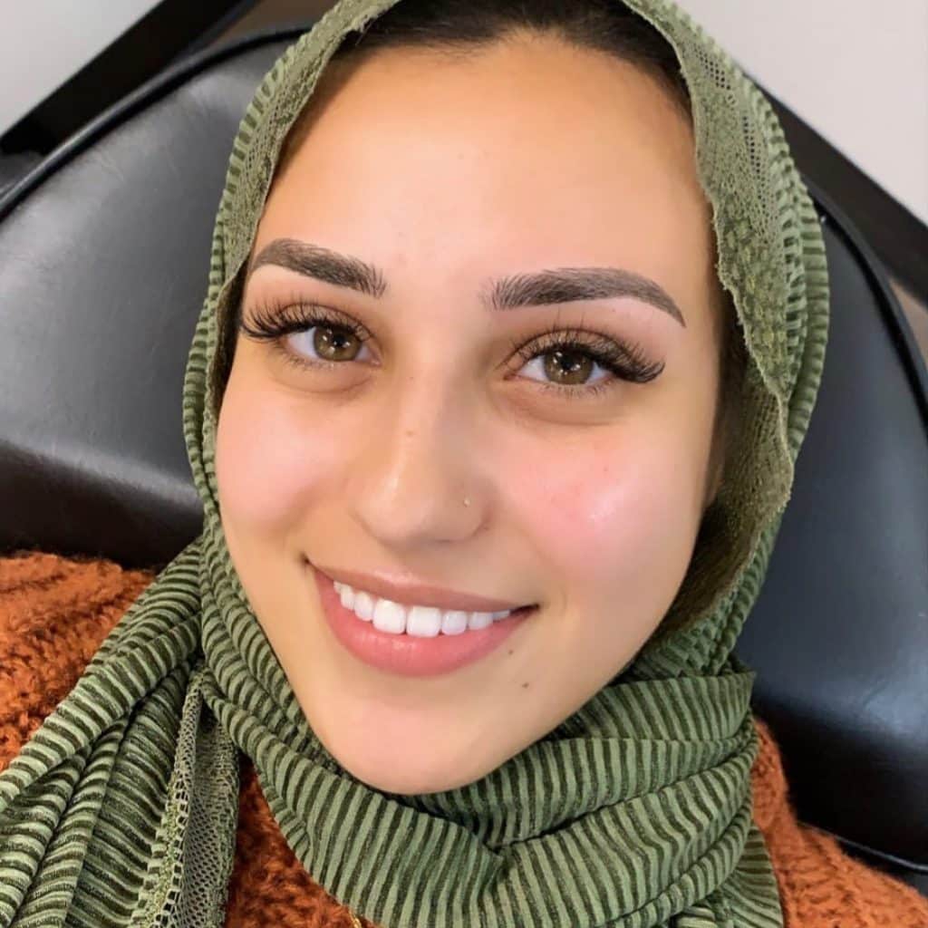 A woman with green scarf smiling for the camera.